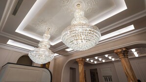 A grand hall with ornate chandeliers, high ceilings, and classical columns. - La Fe boutique Hotel Sarande (Sarandë)