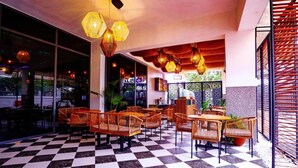 Un café au sol carrelé, avec des meubles en osier et des lampes suspendues.
