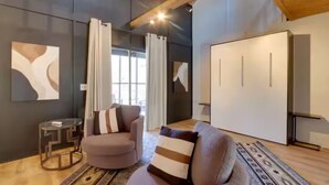 Un salon moderne avec un canapé gris, une petite table d’appoint et un tapis à motifs.