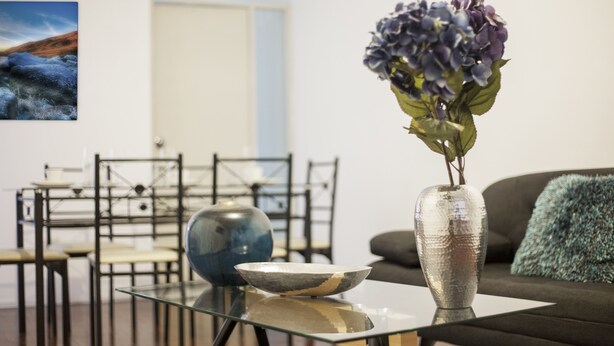 A modern living room with a glass coffee table, a vase with flowers, and a painting on the wall. - Great location and quiet. Excelente ubicacion y tranquilo. Internet Netflix. A/C (Miraflores)