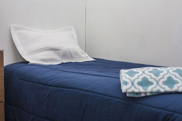 Un lit avec un matelas bleu et un oreiller blanc.