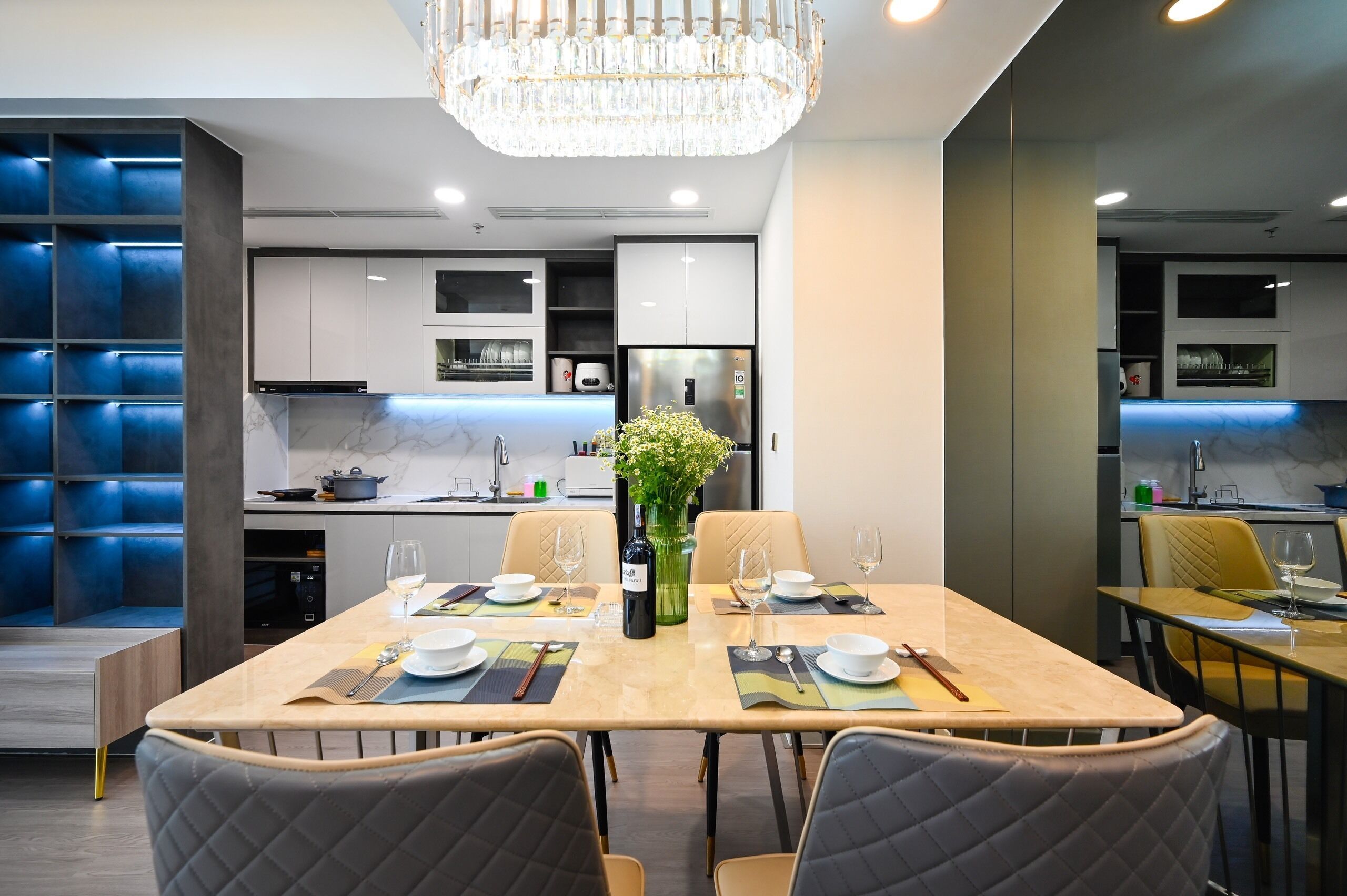 Una cocina moderna con electrodomésticos integrados, un comedor con candelabro y una pared de acento azul.