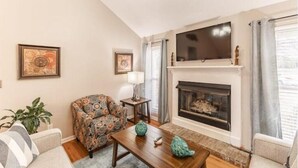 Una sala de estar con chimenea, televisor y muebles con diseño.