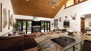 A spacious living area with a large brown leather sofa, a marble kitchen island, and a wooden ceiling.