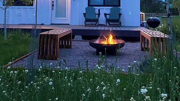 Een modern huis met een terras, buitenzitplaatsen en een vuurkorf.