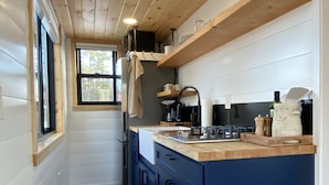 Een kleine keuken met houten balken, een inbouwspoelbak en een blauwe kast.