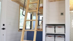 Een houten ladder in een kamer met witte muren, een blauwe kast en een witte deur.