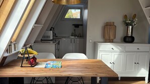 Eine moderne Küche mit einem Holzesstisch, weißen Stühlen und einer Pendelleuchte.