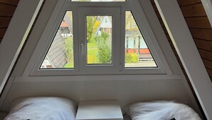 Ein Zimmer mit zwei Betten, einem Fenster und Blick nach draußen.
