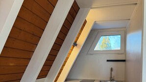 Eine kleine Küche mit weißen Schränken, einer Arbeitsplatte und einem Fenster über der Spüle.