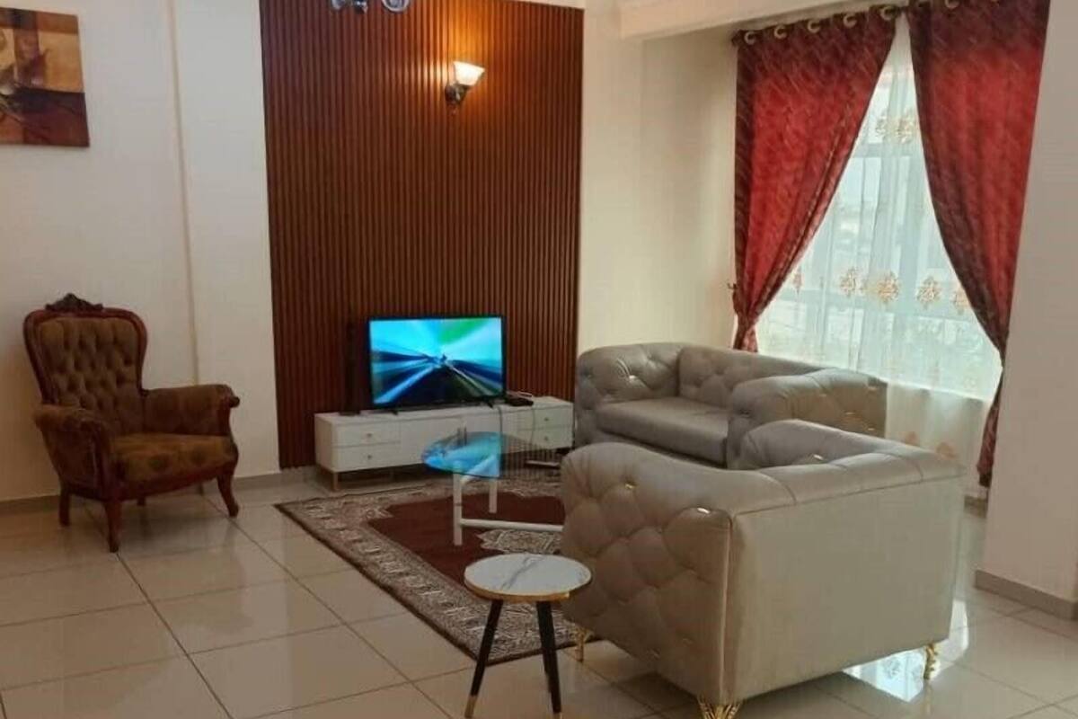 A living room with a television, a sofa, a chair, and a small table.