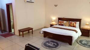 Une chambre à coucher comprenant un lit, des tables de chevet, un banc et un appareil de climatisation.