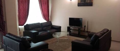 Una sala de estar con un sofá, una mesa de centro y un televisor de pantalla plana.