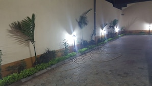 Une allée piétonne dallée, agrémentée de plantes et de lampadaires.