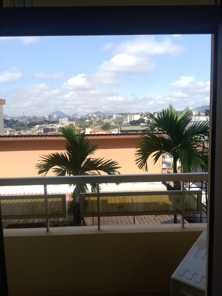 Un balcón con vista a un paisaje urbano, que incluye edificios y palmeras.