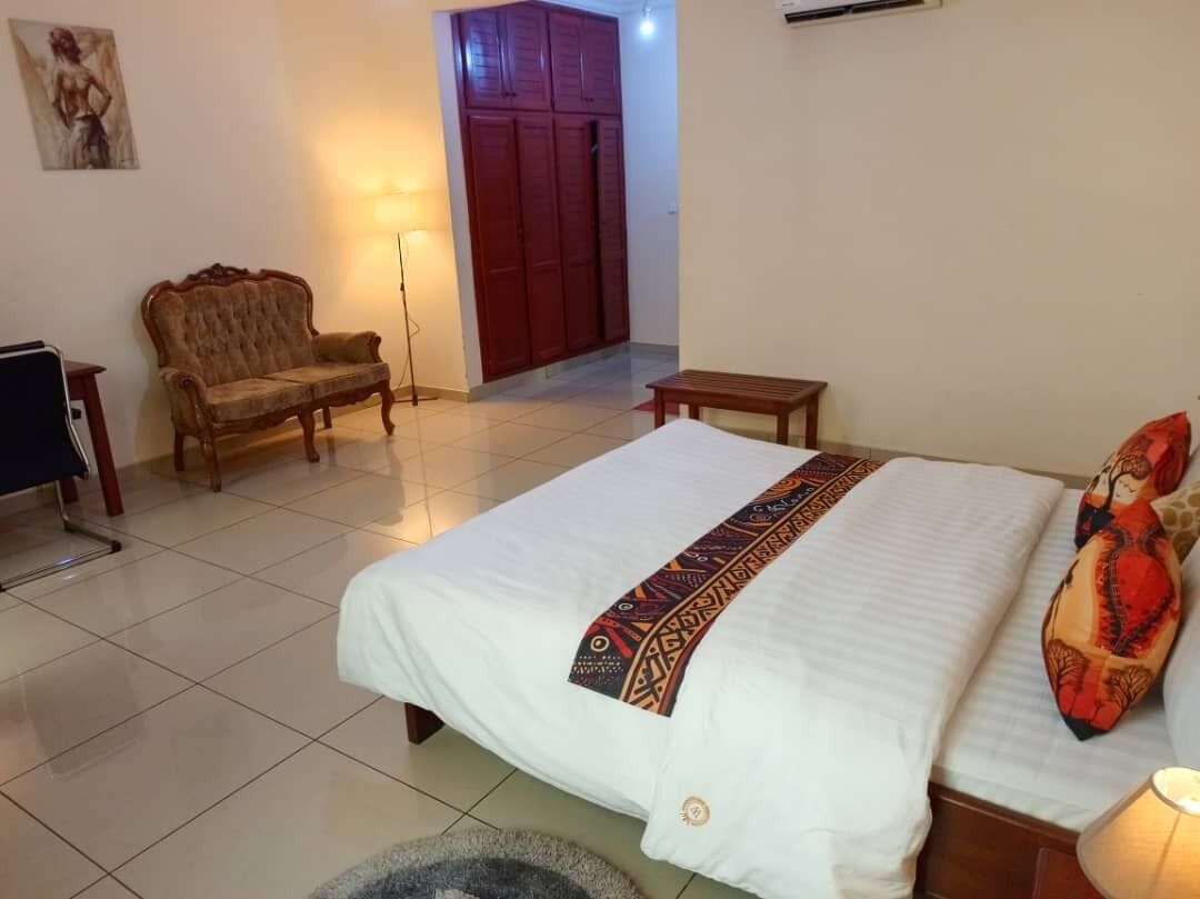 A bedroom with a large bed, a sofa, a small table, and a wardrobe.