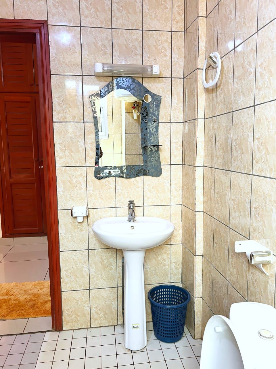 A bathroom with a white sink, a mirror, a toilet, and a blue basket.