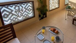 Een balkon met uitzicht op zee, een tafel met ontbijtspullen en een stoel.