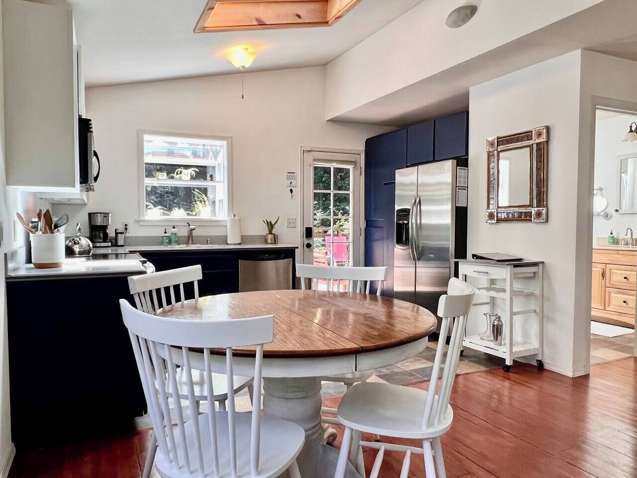 A modern kitchen with a central island, white cabinetry, and a dining area with a round table and white chairs.