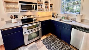 A modern kitchen with built-in appliances, a window with a view, and a patterned rug. - Cozy Cabin in Redwoods | Hot Tub (Guerneville)
