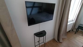 Un televisor de pantalla plana montado en una pared, con un control remoto sobre un pedestal debajo.