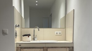 Een badkamer met een grote spiegel, een wastafel en houten kasten.