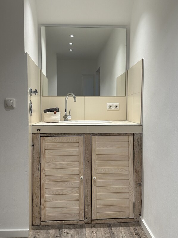 Une salle de bain avec un grand miroir, un lavabo et des meubles en bois.