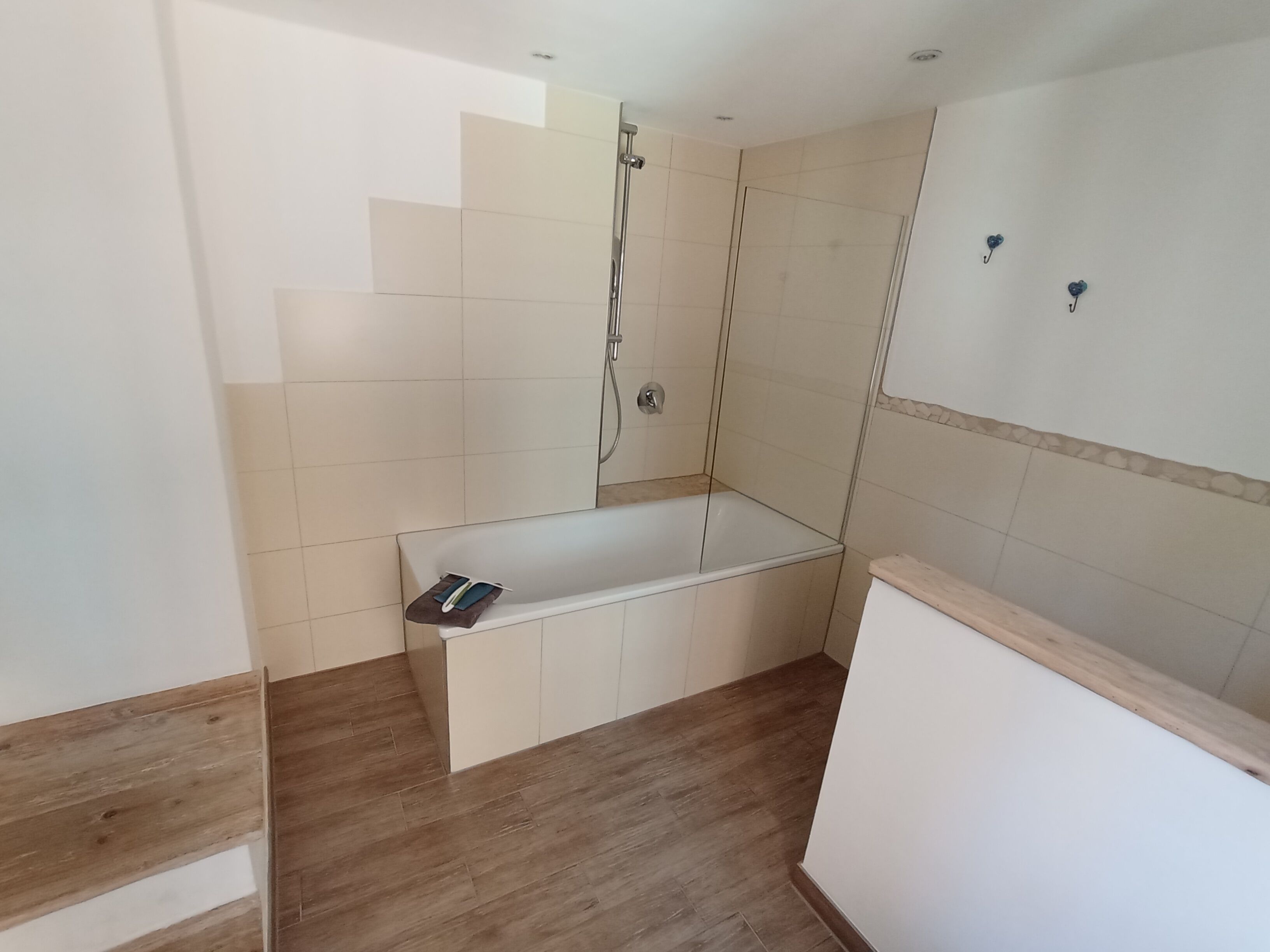Ein Badezimmer mit Badewanne, Dusche und Holzboden.