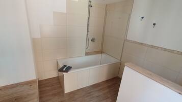 Ein Badezimmer mit Badewanne, Dusche und Holzboden.