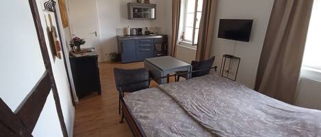 Un dormitorio con cama, escritorio, silla, televisor y kitchenette.