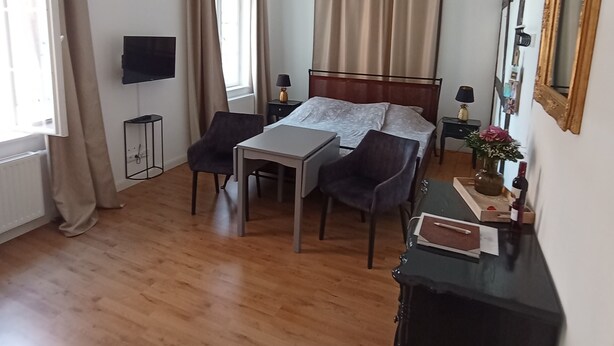 Une chambre à coucher avec un lit, une table de chevet, une lampe, une commode et un téléviseur fixé au mur.