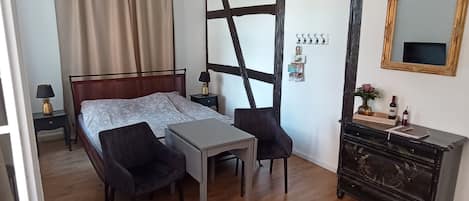 Un dormitorio con cama, escritorio, silla, cómoda, espejo y candelabro.