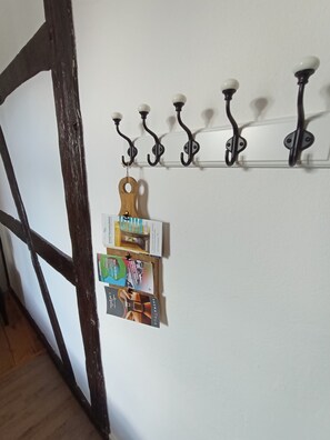 A wall-mounted coat rack with hooks and a wooden key holder with keys.