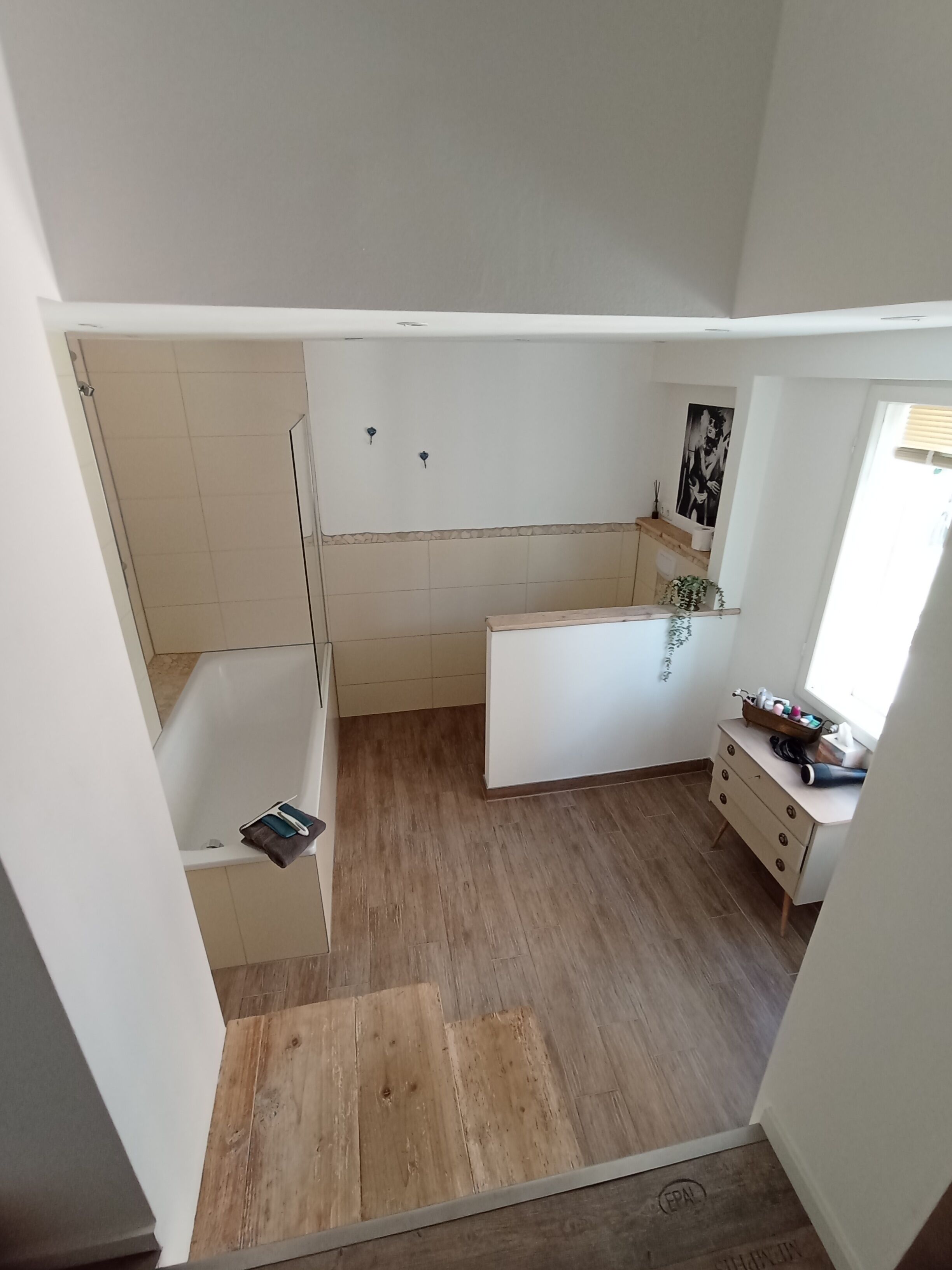 Ein kleines Badezimmer mit Badewanne, Waschtisch und Duschbereich.