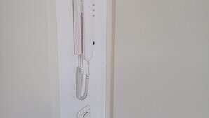 Un téléphone blanc fixé au mur, doté d’un combiné à fil et d’une base séparée.