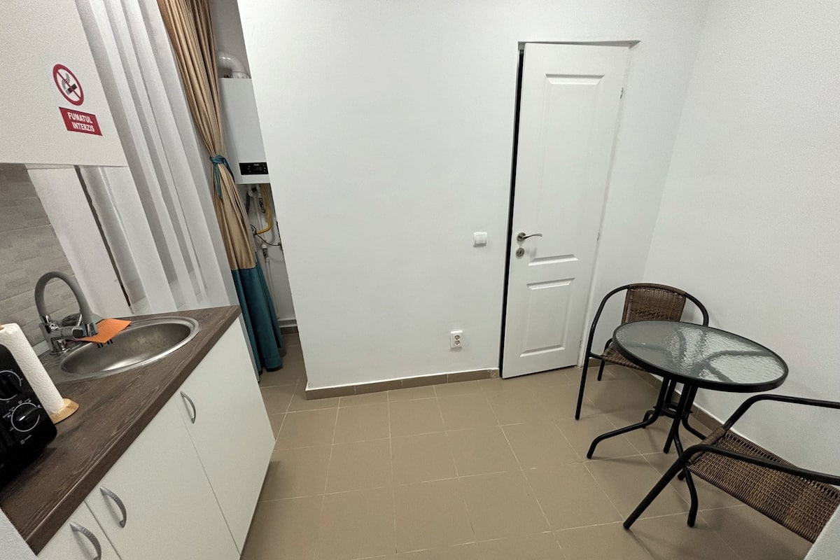 A small kitchen with a sink, a table with chairs, and a door.