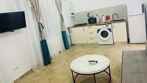 A compact kitchen with a washing machine, microwave, and a small dining table. - The Loft Gara de Nord (Bucharest)