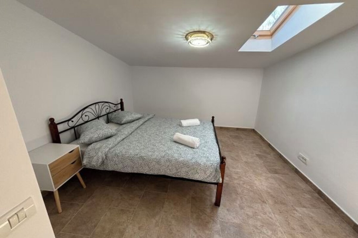 Une chambre à coucher avec un lit, une table de chevet et une lucarne.