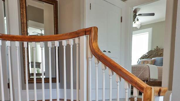 Un escalier avec des balustres blanches et des rampes en bois.