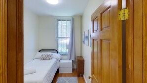 Une chambre à coucher avec un lit, une table de chevet et une fenêtre avec des rideaux.