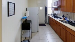 Une cuisine compacte avec des meubles en bois, un réfrigérateur blanc, une cuisinière à gaz et un petit plan de travail.