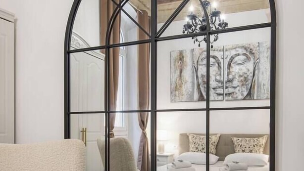 A bedroom with a large arched mirror, a bed with white linens, a chair, and a chandelier. - Zen Island downtown Florence, new apartment for 6 (Firenze)