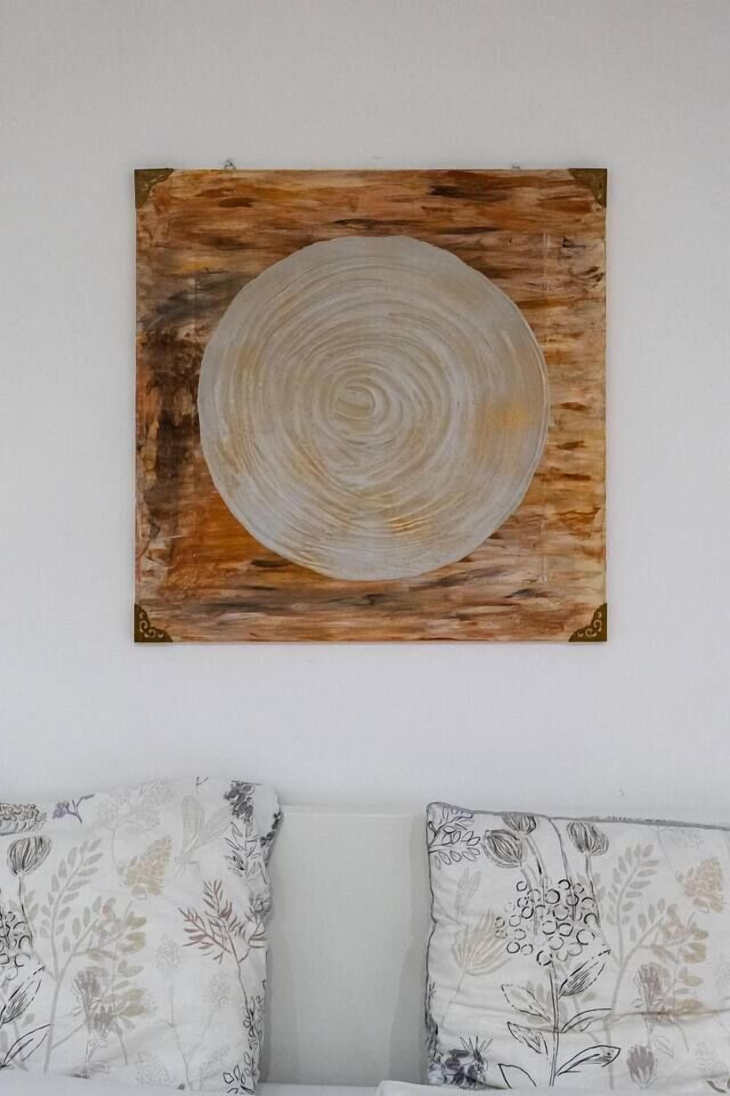 A wall-mounted artwork with a circular design on a wooden background.