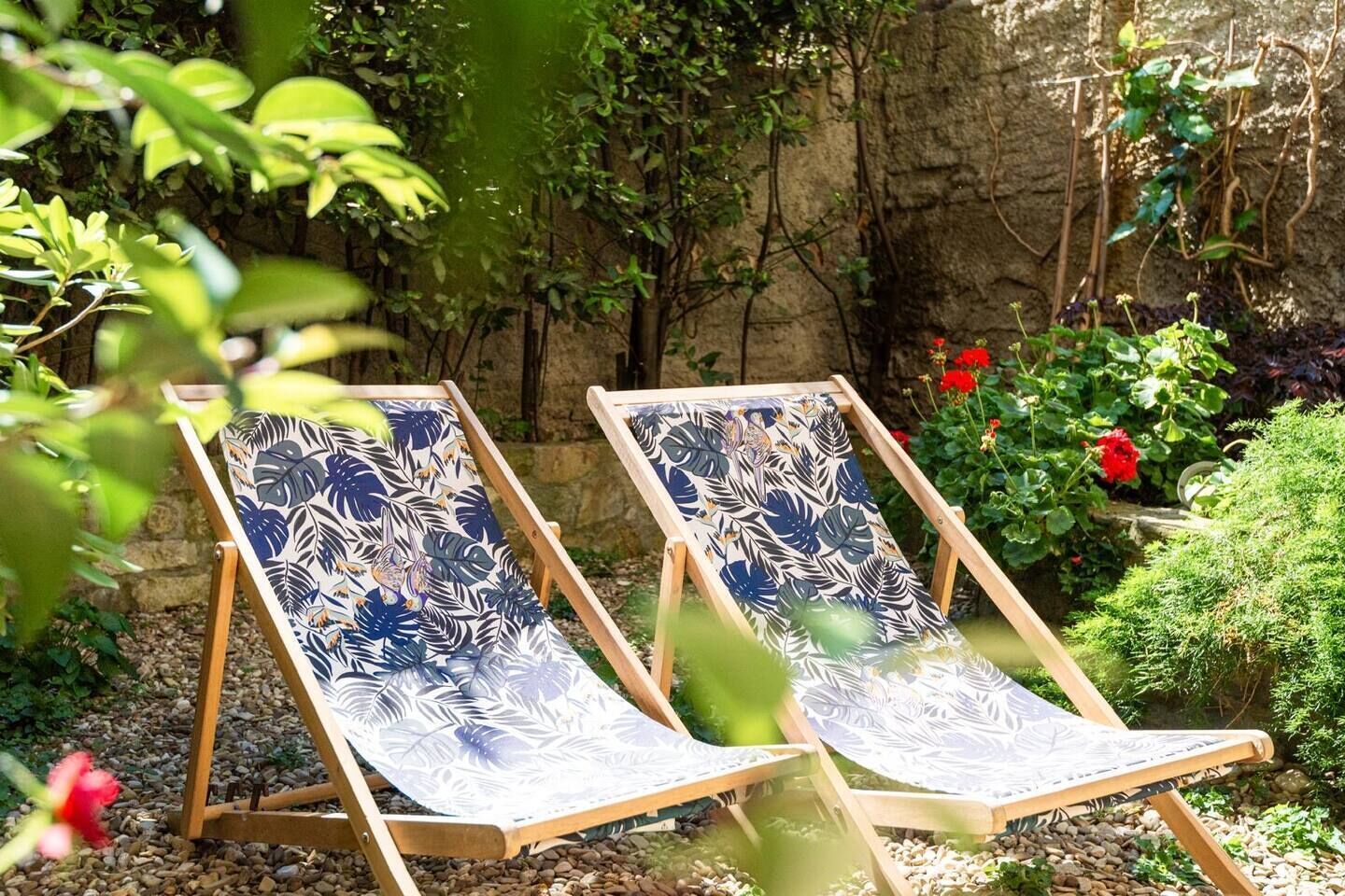 Deux fauteuils de jardin en bois, dotés de coussins à motifs.