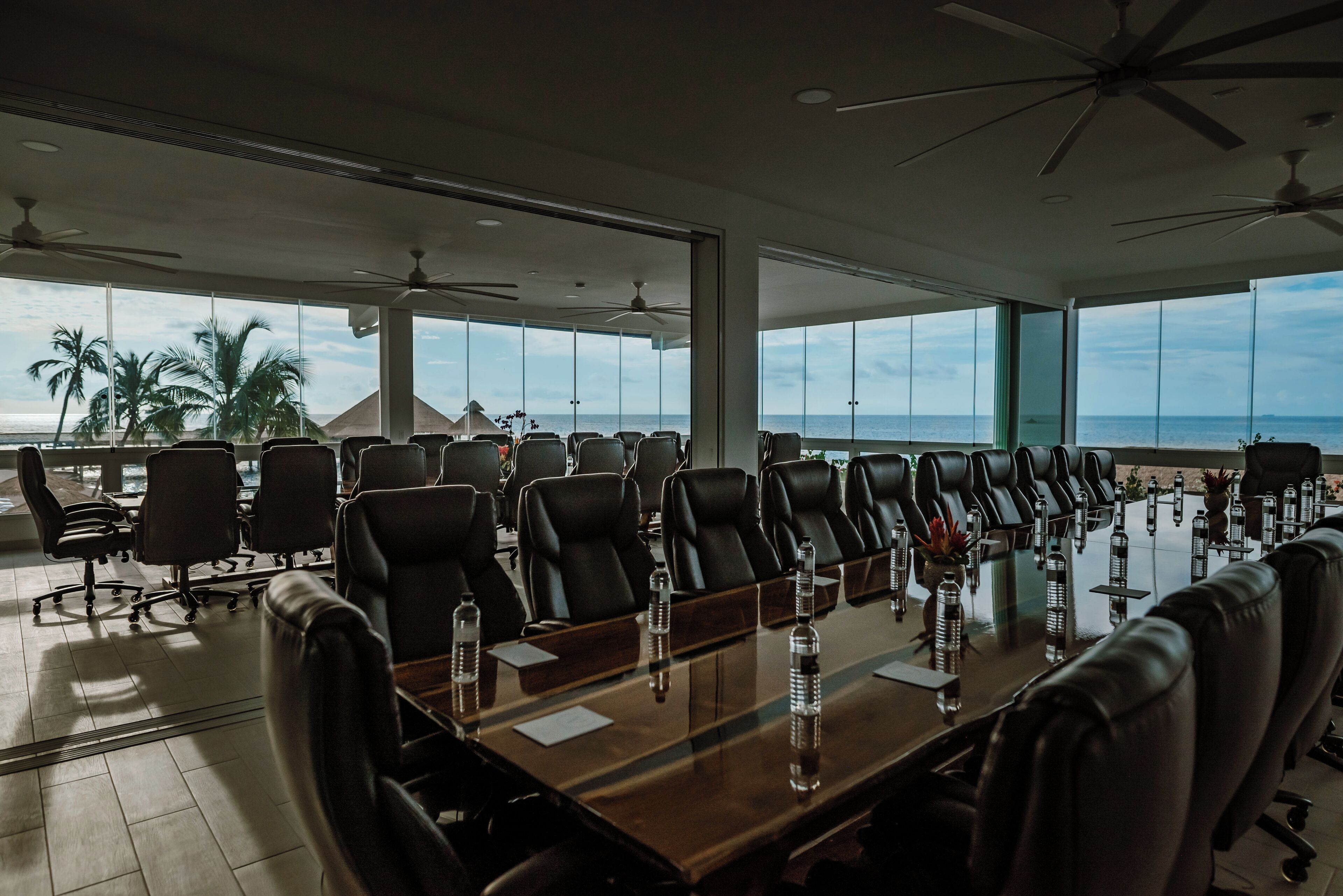 A conference room with a long table, multiple chairs, and ceiling fans.