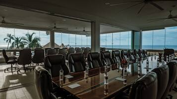 A conference room with a long table, multiple chairs, and ceiling fans.