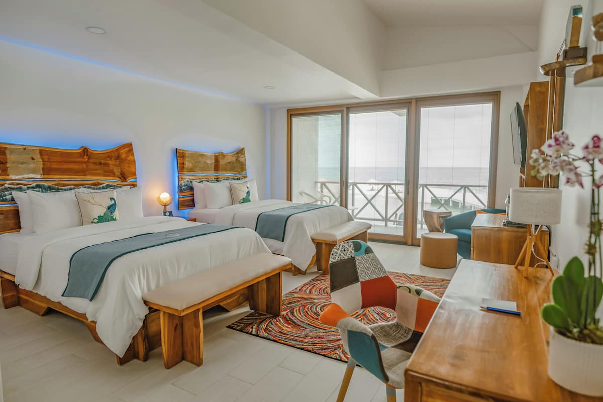Un dormitorio moderno con dos camas, un escritorio y un balcón con vistas.