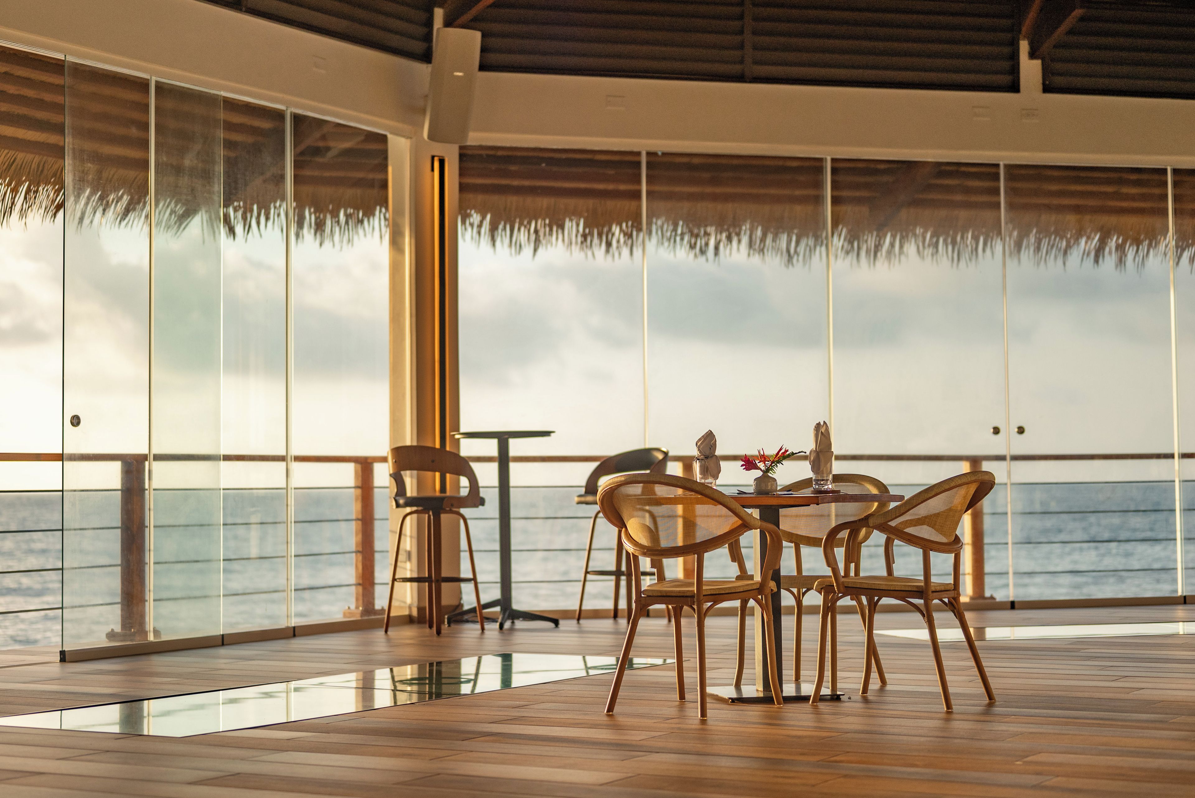 Un comedor con una mesa y sillas, ventanas grandes y vista al mar.