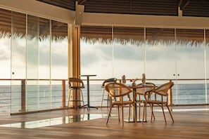 A dining area with a table and chairs, large windows, and a view of the sea. - Ordovician Beach Resort (Isla Grande)