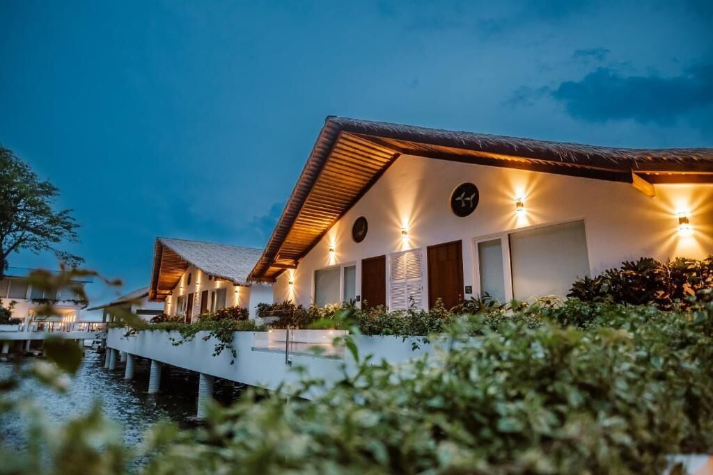Wasserbungalows mit Strohdach, Holzläden und einem Pool.